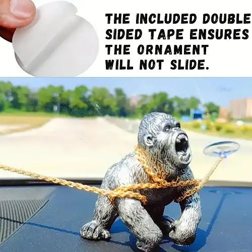 Graphic demonstrating the installation of the gorilla dashboard toy, showing a person peeling the included double-sided adhesive tape that ensures the ornament will not slide while driving.