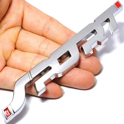 Metallic car emblem held in a hand against a white background