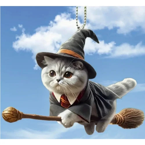 A flying witch cat rearview mirror hanging accessory suspended outdoors against a bright blue sky with white clouds, highlighting the whimsical broomstick design.
