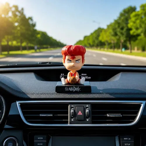 The Hanamichi Sakuragi anime auto interior dashboard accessory mounted securely above the central air vents, featuring the red-haired basketball player against a sunny, tree-lined road background.