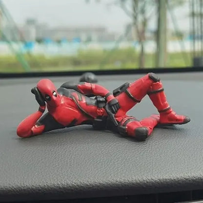 The lying down Deadpool car interior dashboard decoration securely placed on a textured vehicle dashboard, featuring the Marvel superhero casually resting his head on his hand.