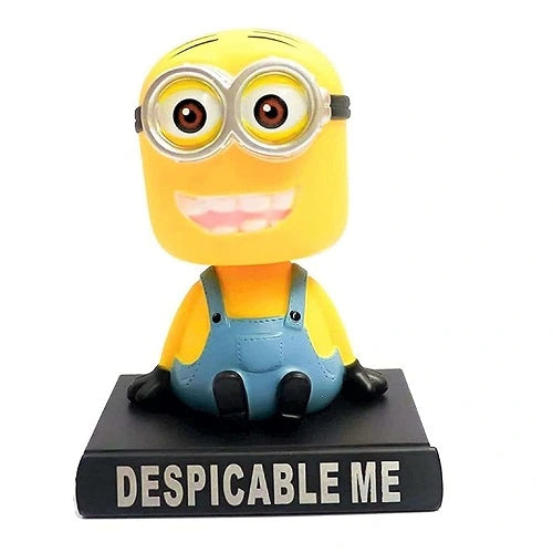 Front view of a smiling yellow Minion bobblehead figure wearing blue overalls on a black "Despicable Me" base, designed as a car dashboard ornament.
