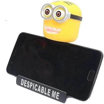 Minion car dashboard bobblehead functioning as a mobile phone holder, securely gripping a black smartphone horizontally for hands-free viewing.