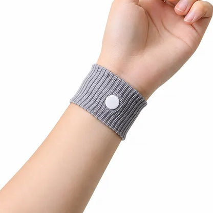Close-up of a grey motion sickness acupressure wristband properly worn on a wrist, featuring the white plastic pressure button that provides drug-free anti-nausea relief during travel.