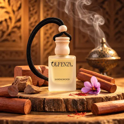 Olfenza Sandalwood car air freshener bottle placed on a natural wood slice, surrounded by sandalwood logs, a purple saffron flower, and atmospheric smoke from an antique incense burner.