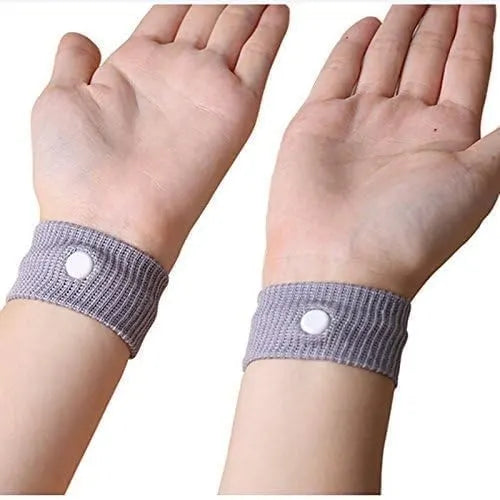 Proper placement demonstration of the pack of 2 grey motion sickness acupressure wristbands, showing both white pressure point buttons positioned correctly on the inner wrists for maximum effectiveness.