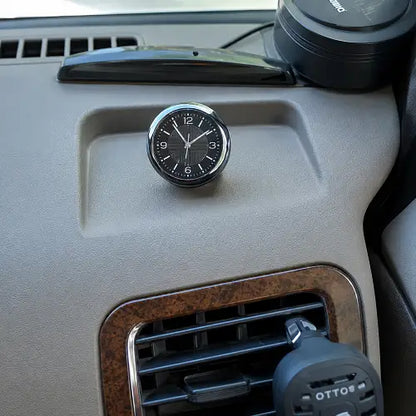 A stick-on automotive dashboard clock placed neatly above the central air vents, adding a premium analog time display to the car's interior trim.